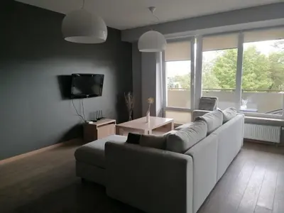 a living room with a white couch and a tv at Central Druskininkai Apartment in Druskininkai