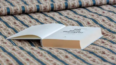 an open book laying on a bed with a book at Violetos Lux Apartamentai in Druskininkai