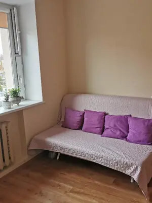 a couch with purple pillows in a room with a window at Central Apartments Karolina in Druskininkai
