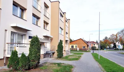 a sidewalk in front of a building with trees at Central Apartments Karolina in Druskininkai