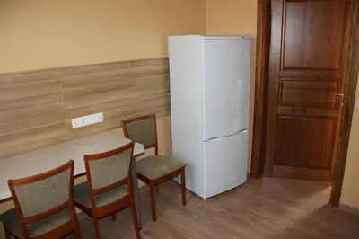 a kitchen with a table and a refrigerator at Apartamentai 