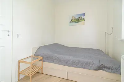 a white bedroom with a bed with a wooden frame at Sky Studio near the Vilnius Center in Vilnius