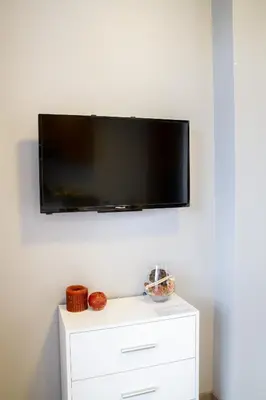 a flat screen tv on a wall above a white dresser at Sky Studio near the Vilnius Center in Vilnius