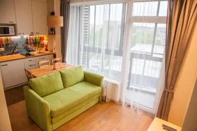 a green couch in a kitchen with a large window at Sky Studio near the Vilnius Center in Vilnius