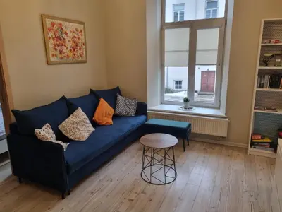 a living room with a blue couch and a table at Igo apartment Uzupis in Vilnius