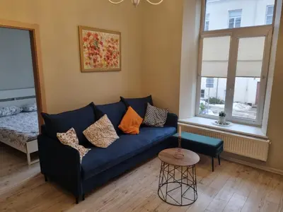 a living room with a blue couch and a window at Igo apartment Uzupis in Vilnius