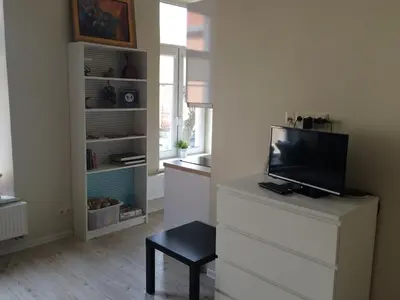 a living room with a dresser with a tv and a chair at Igo apartment Uzupis in Vilnius