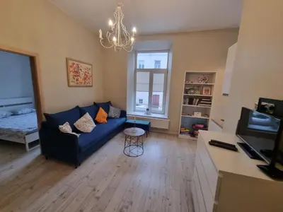 a living room with a blue couch and a chandelier at Igo apartment Uzupis in Vilnius
