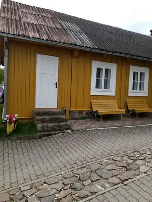 a yellow building with two benches in front of it at 