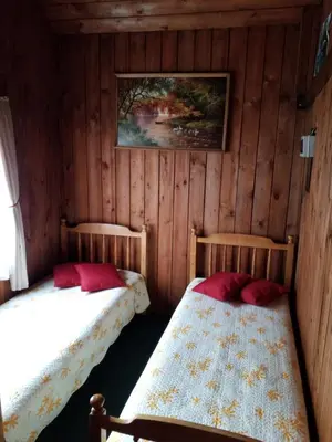 two beds in a room with wooden walls at 
