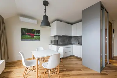 a kitchen with white cabinets and a table and chairs at Napoleon Hill Apartment in Kaunas