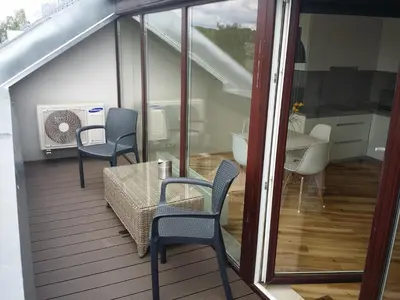a balcony with a table and chairs and a kitchen at Napoleon Hill Apartment in Kaunas