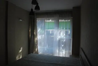 a bedroom with a bed and a window with curtains at Šeimyninis butas in Birštonas