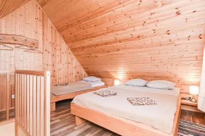 two beds in a room with wooden walls at Manto Apartamentai in Druskininkai