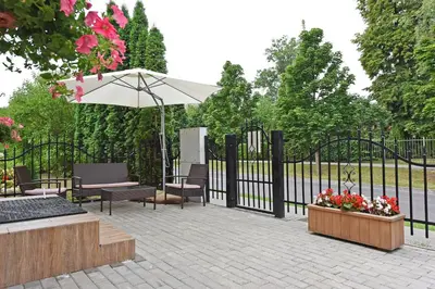 a patio with an umbrella and benches and a fence at Manto Apartamentai in Druskininkai