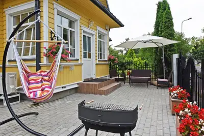 a patio with a hammock and an umbrella on a house at Manto Apartamentai in Druskininkai