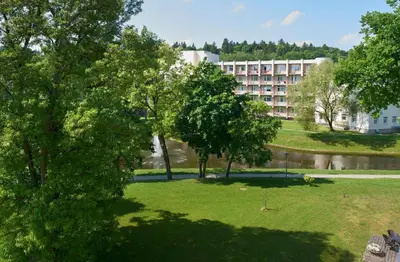 a park with trees and a building in the background at Central Apartment in Birštonas