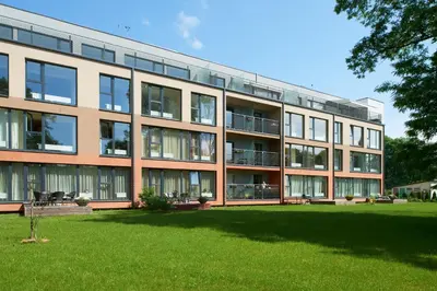 a large building with a lawn in front of it at Central Apartment in Birštonas