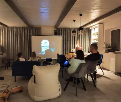 a group of people sitting in a room watching a presentation at Family house in Druskininkai