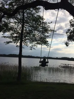 a person on a swing over a lake at Kuliniai by Stirniai lake Moletai district in Kulintse