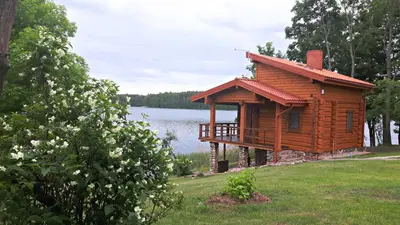 a log cabin on the side of a lake at Mekų sodyba in Degučiai