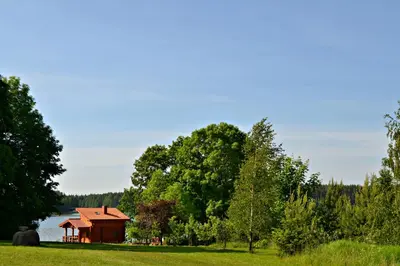 a barn in a field next to a lake at Mekų sodyba in Degučiai