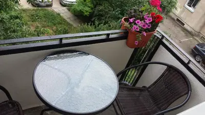 a table and a bench on a balcony with flowers at Apartment Vilnius Zemaitijos in Vilnius