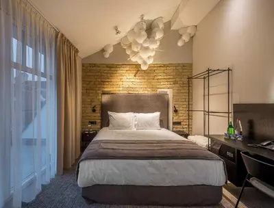 a bedroom with a large bed and a brick wall at Artagonist Art Hotel in Vilnius