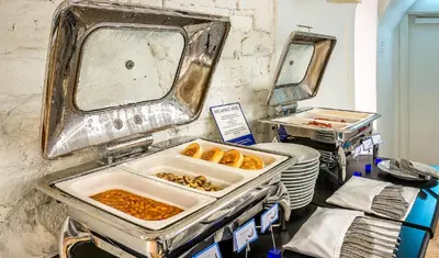a buffet with a tray of food and a mirror at Artagonist Art Hotel in Vilnius