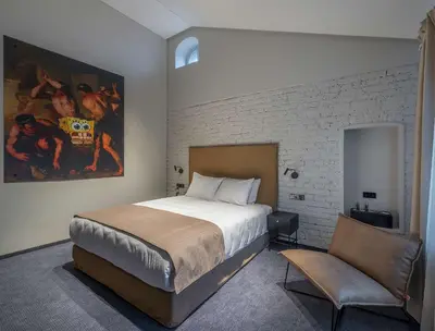 a bedroom with a bed and a chair and a painting at Artagonist Art Hotel in Vilnius