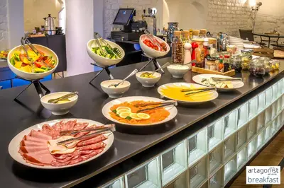 a buffet with many plates of food on a counter at Artagonist Art Hotel in Vilnius