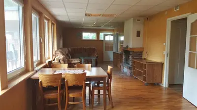 a room with a table and chairs and a person sitting at it at Petronių sodyba in Rukliai