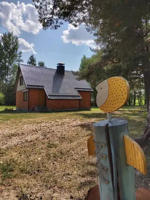 a bird on a post in front of a house at Petronių sodyba in Rukliai