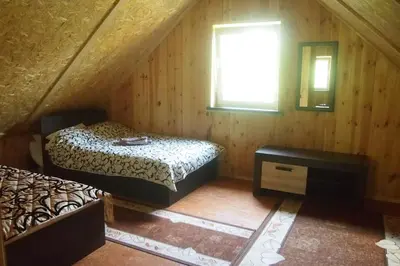 a attic room with two beds and a window at Namelis su pirtele in Druskininkai