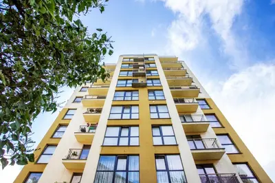 a tall yellow apartment building with the sky in the background at Zalgirio apartment in Vilnius