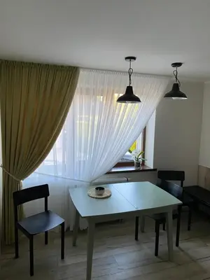 a table and chairs in a room with a window at Apartamentai Tarp trijų ežerų in Tytuvėnai
