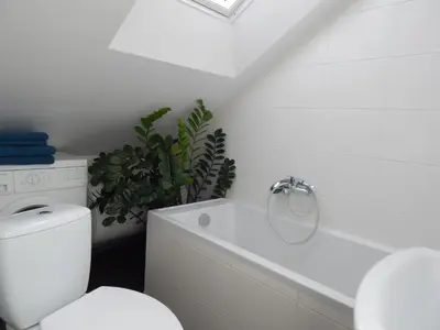 a white bathroom with a toilet and a plant at ROKO Apartments in Kaunas