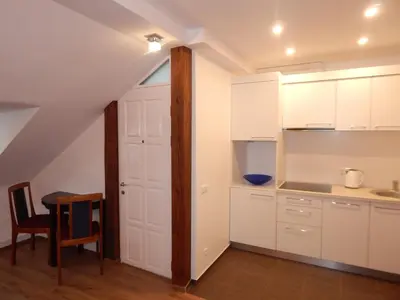 a kitchen with white cabinets and a table and a door at ROKO Apartments in Kaunas