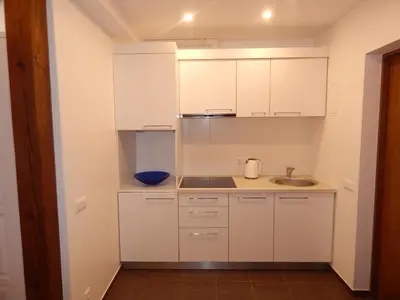 a small kitchen with white cabinets and a sink at ROKO Apartments in Kaunas