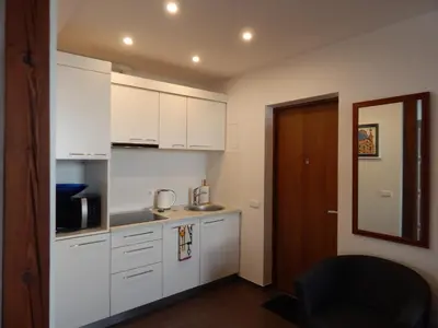 a kitchen with white cabinets and a black chair at ROKO Apartments in Kaunas