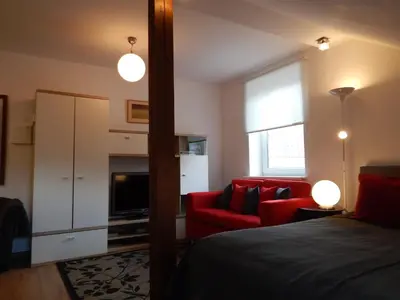 a bedroom with a red bed and a red couch at ROKO Apartments in Kaunas