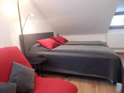 a bedroom with a bed with red pillows and a red chair at ROKO Apartments in Kaunas