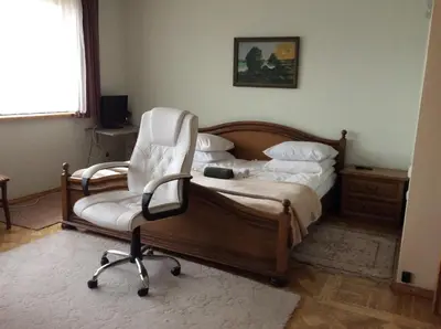 a bedroom with a bed and a white chair at Kotedžai Milikonių g. in Kaunas