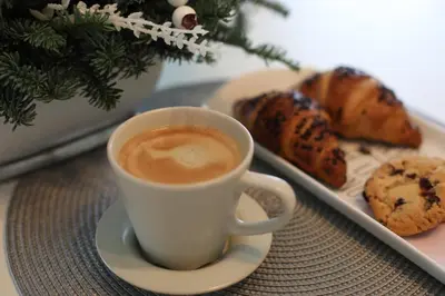 a cup of coffee next to a plate of cookies at Auroradream in Motiejiškės