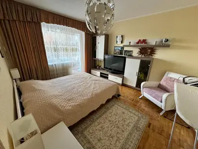 a bedroom with a bed and a couch and a television at VIsagino Apartment in Visaginas