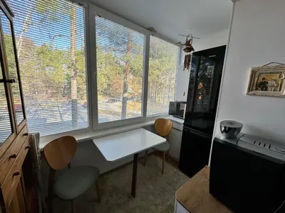 a kitchen with a table and two chairs and two windows at VIsagino Apartment in Visaginas