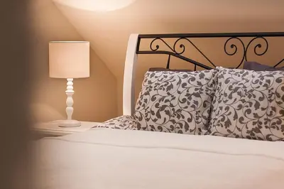 a bedroom with a bed with a lamp and pillows at Apartments Satva in Vilnius