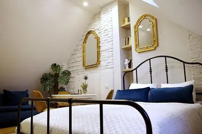a bedroom with a bed and a table and mirrors at Apartments Satva in Vilnius