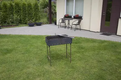 a grill sitting in the grass outside of a house at Agnės svečių namai in Kaunas