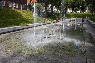a fountain in a park with people playing in it at Agnės svečių namai in Kaunas